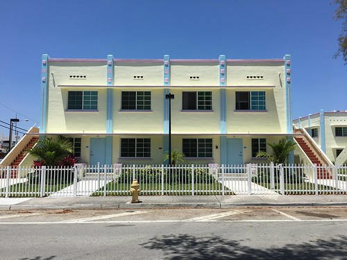 A yellow duplex with tropical plants in front