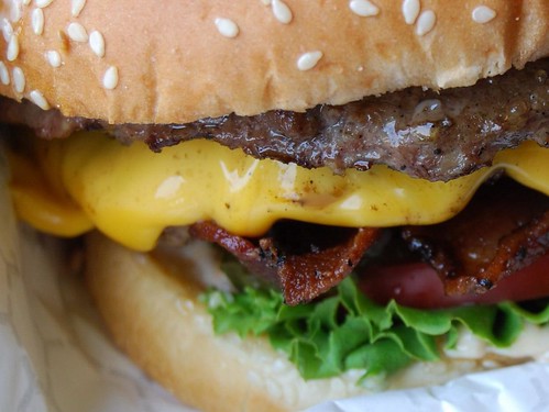 close up of a cheesburger with lettuce and poppy seed bun