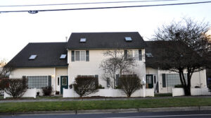 white multifamily duplex with trees in front and a green lawn