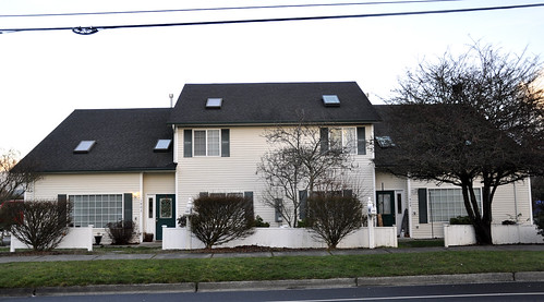white multifamily duplex with trees in front and a green lawn