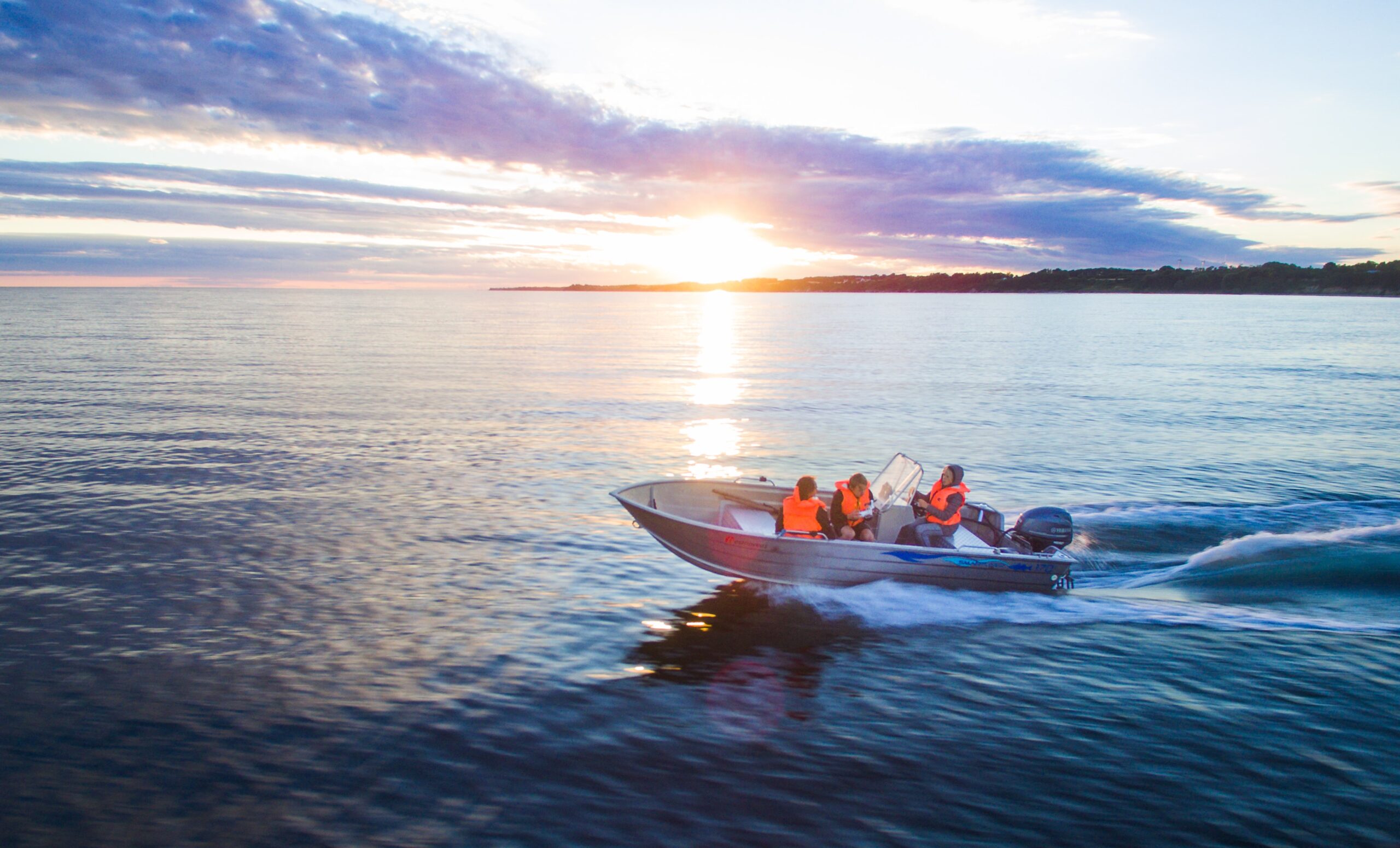 people on a small boat on the water at sunset
