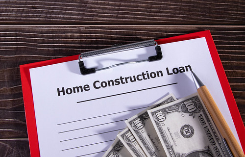 A home construction loan form and some 100 dollar bills on a wooden table