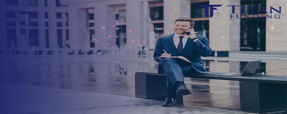 man sitting on a bench outside of a building while talking on his cell phone