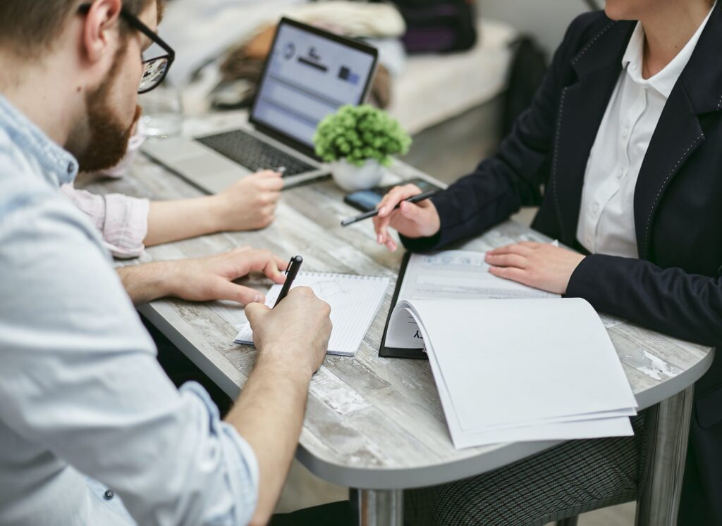 Two people in business attire sitting at an office desk planning something on paper