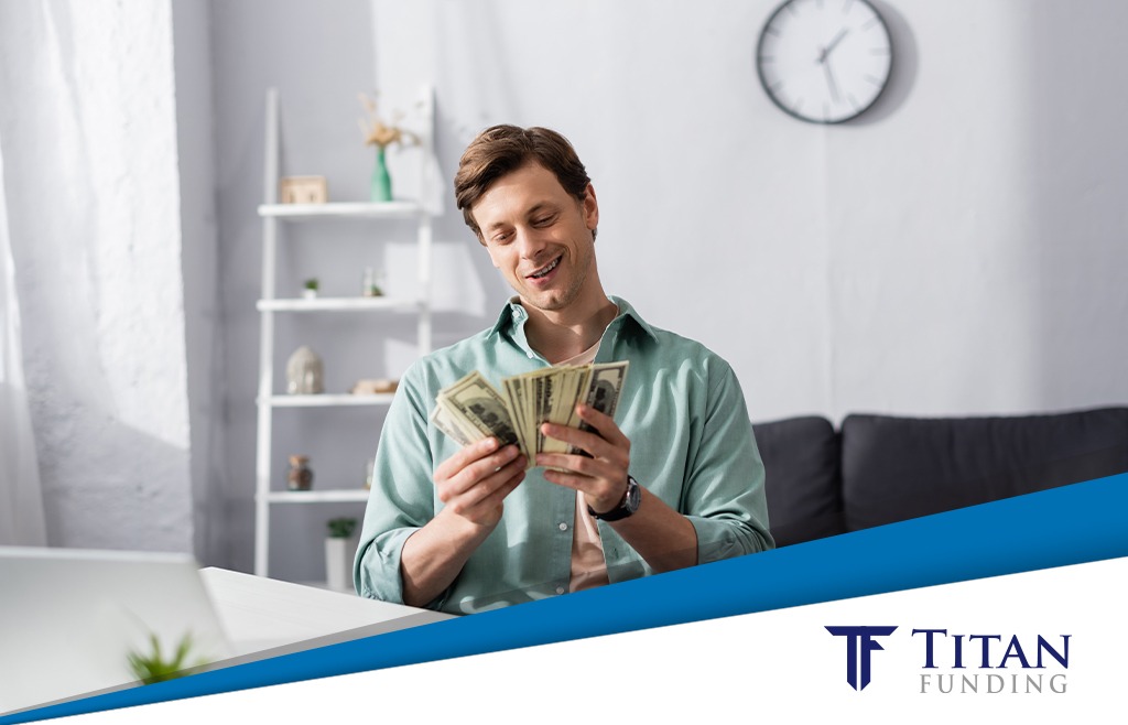 Man sitting at a desk and counting a pile of money